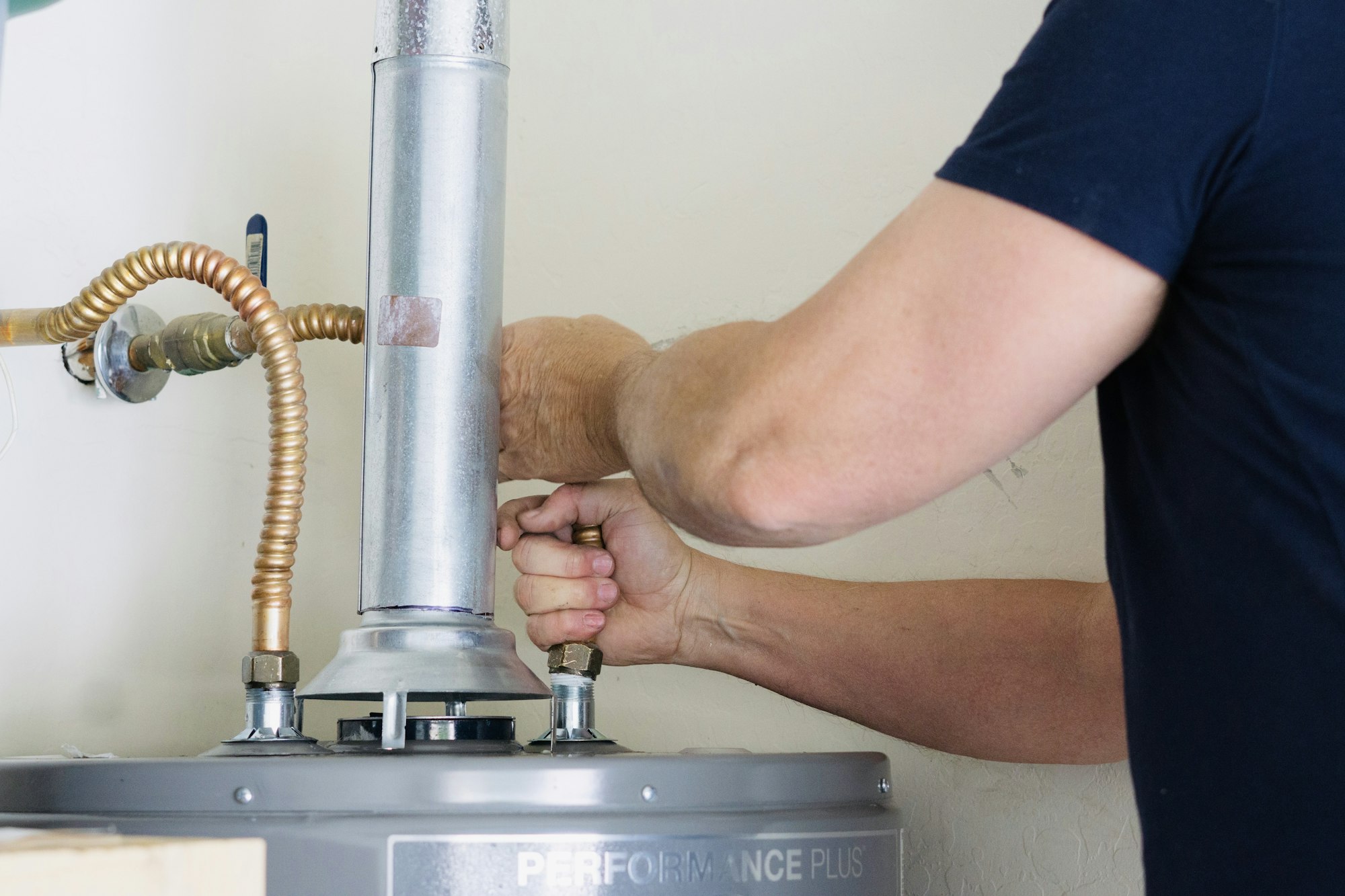 Adult male making adjustments and tightening connection on new hot water heater